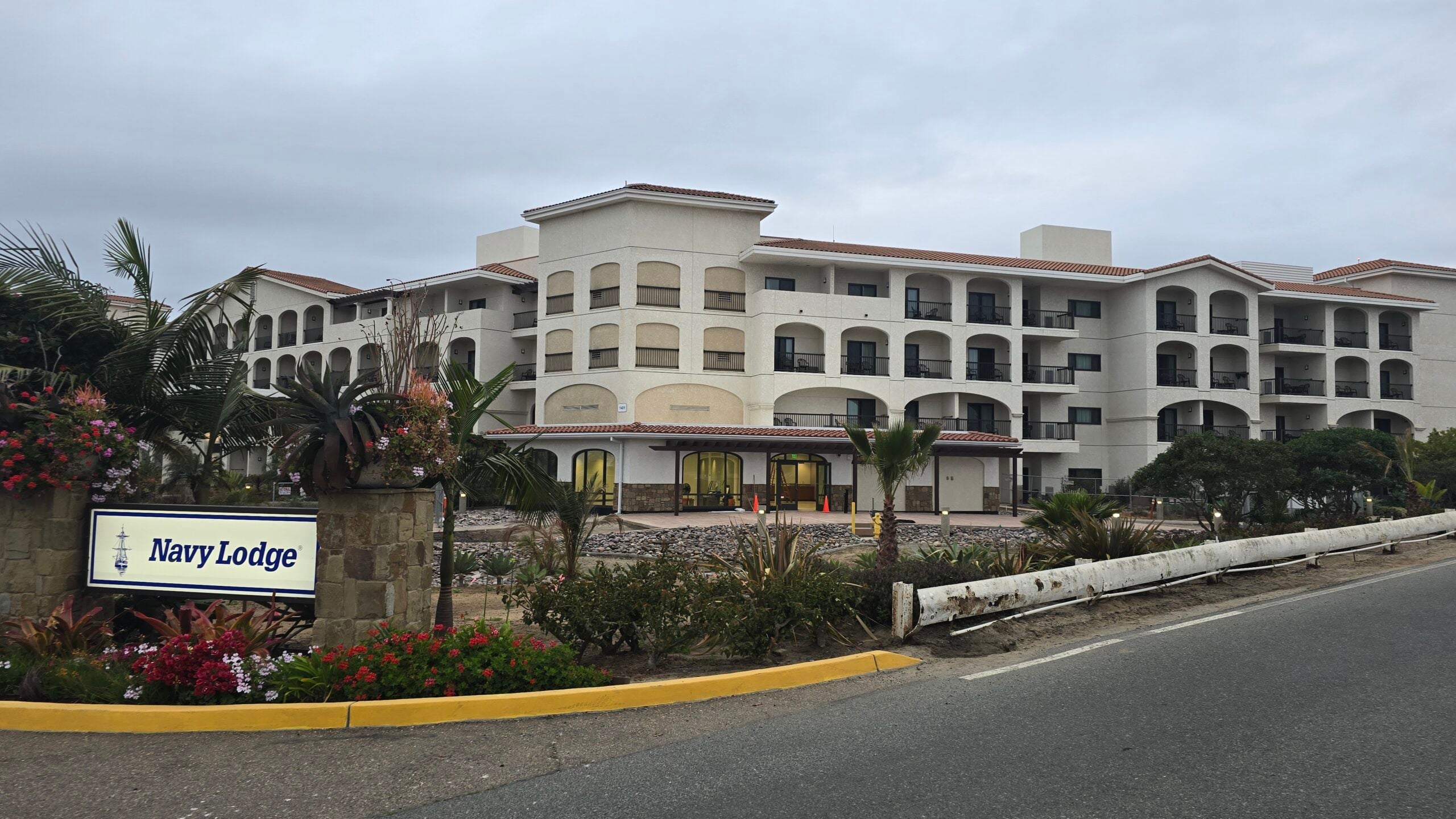 Exterior view of the Navy Lodge building and entrance sign under an overcast sky.