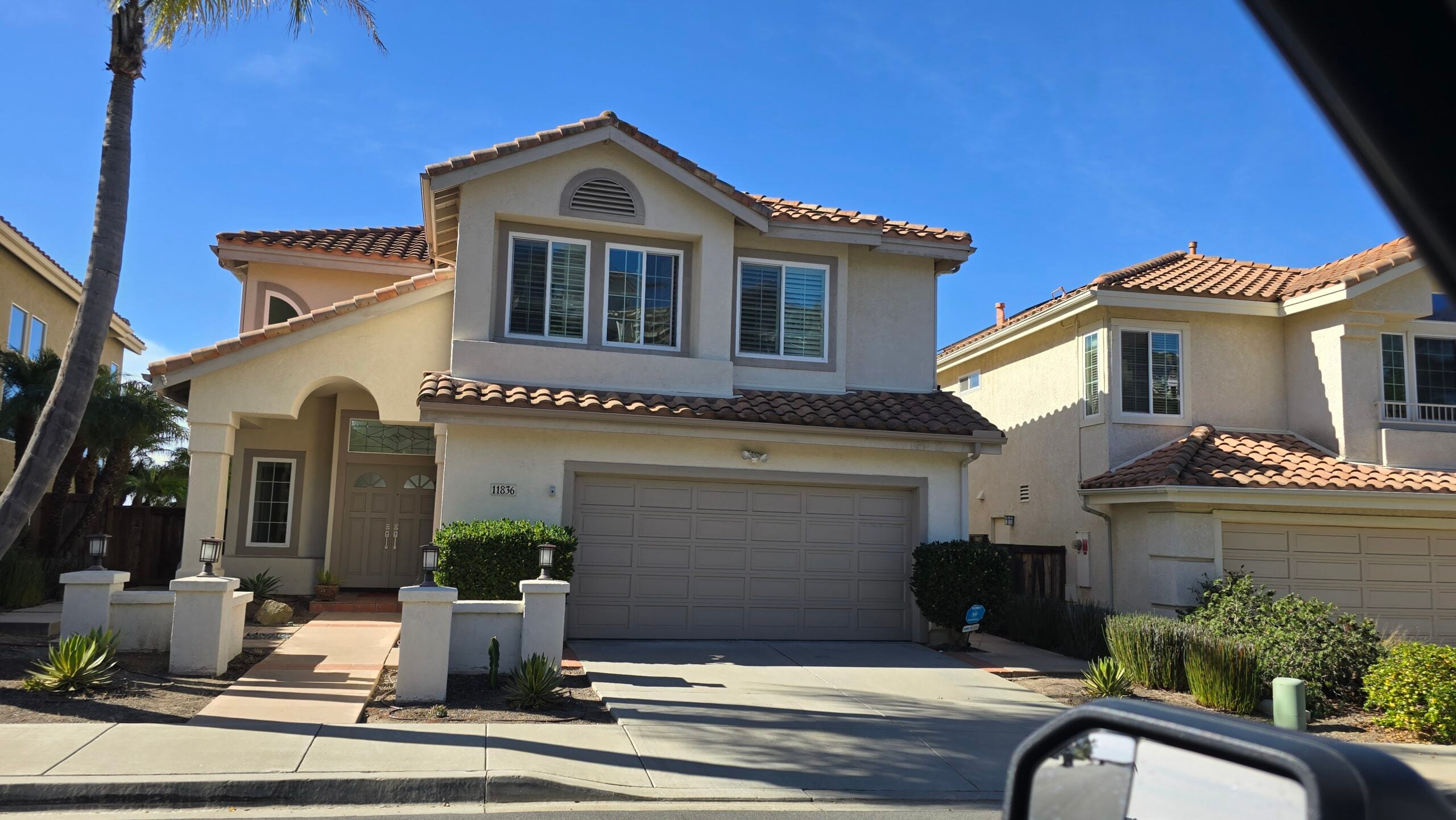 Exterior view of a beige two-story suburban home with a tile roof and garage.