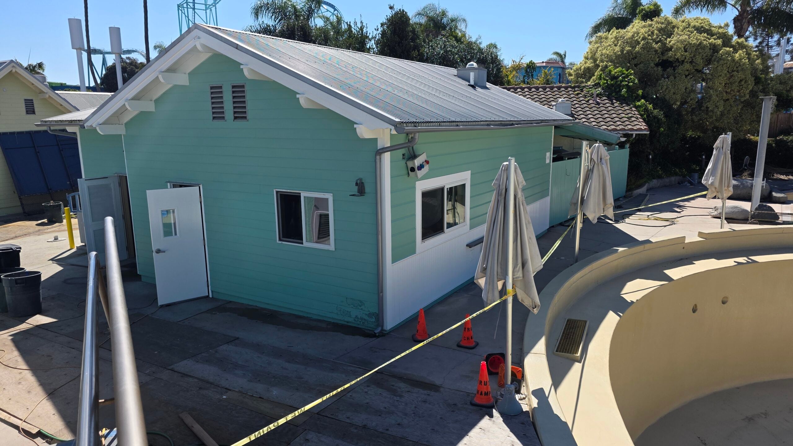 A mint green service building at an outdoor facility next to a dry pool area.